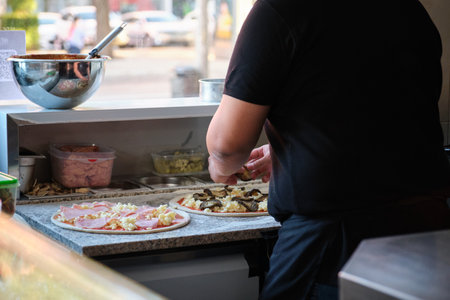 Unrecognizable male preparing pizzas in a restaurant kitchen. Pizzeria.の写真素材