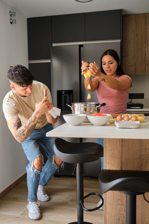 Two young latin people recording a recipe preparation with the smartphone for social media at...