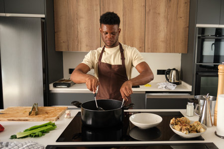 Young black man preparing fried chicken mince with vegetables recipe in a kitchen.の写真素材