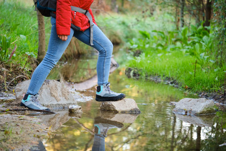 Unrecognizable female hiker legs crossing a creek in a forest.の写真素材