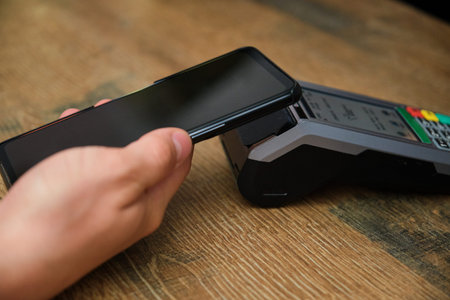 Unrecognizable customer paying the restaurant bill with a virtual mobile card using a dataphone.