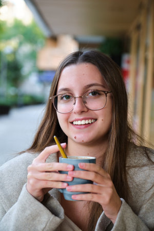 Young woman smiling and drinking coffee in a cafeteria.