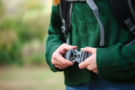 Close up of hiker woman fastening backpack strap in the mountain. Trekking concept.の写真素材