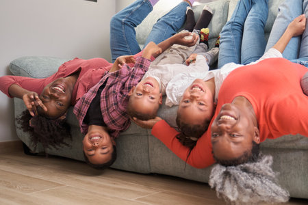 Happy african family bonding and enjoying together upside down on sofa. Horizontal extended family.の写真素材