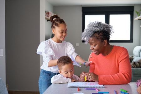 African mother painting with her son while her daughter call to give her a picture she has drawn.の写真素材