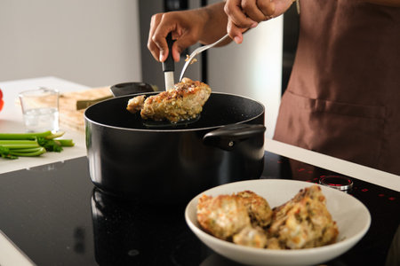 Unrecognizable young african man preparing fried chicken mince with vegetables recipe in a kitchen.の写真素材