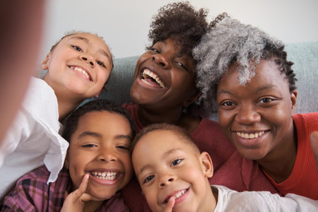 Happy african horizontal extended family smiling and taking a selfie at home.の写真素材