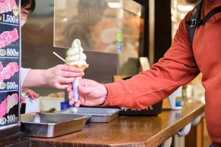 Takayama, Japan. April 06, 2023: European tourist buying matcha ice cream at a kiosk in Takayama town, Hida, Gifu, Japan.のeditorial素材