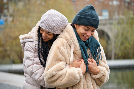 Dominican lesbian couple hugging with affection and love at street in a winter day.の写真素材