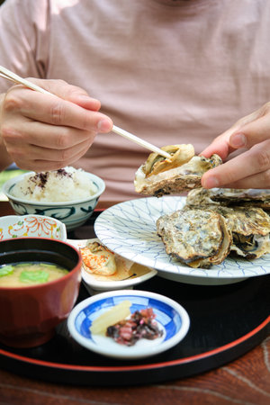 Unrecognizable european tourist eating traditional oyster set in Miyajima, Hiroshima, Japan.の写真素材