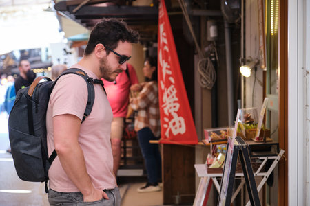 European tourist looking at restaurant menu in a traditional street in Miyajima, Hiroshima, Japan.の写真素材