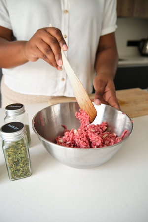 Close up of cuban woman hands mixing raw minced beef and garlic to prepare cuban style stuffed...