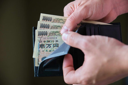 Hand holding a wallet with ten thousand yen bills. Cash, tax, recession, economy, inflation,...