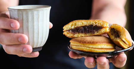 Person offering japanese dorayaki and green tea. Japanese red-bean sweet, anko.の写真素材