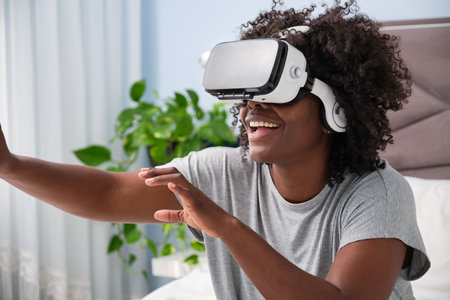 Young african woman experiencing virtual reality on her bed in the morning.の写真素材