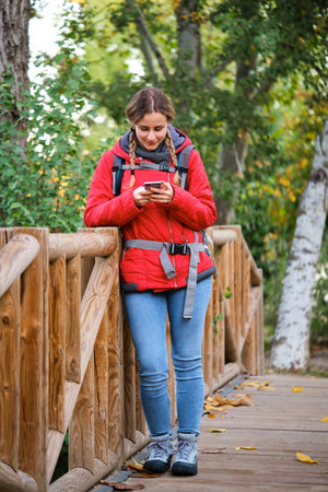 Young female hiker consulting smartphone while trekking.の写真素材