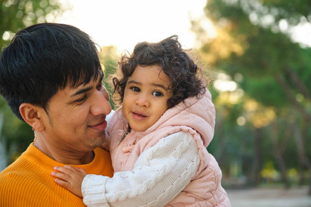 Portrait of happy Ecuadorian father holding her one year old daughter in a park.の写真素材