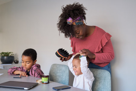 Toddler son playing while his african mother tries to style his hair using an afro curl or twists...