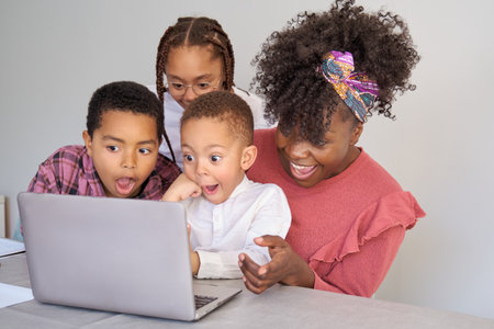 Happy african family look at laptop screen surprised at home.の写真素材