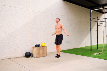 Man skipping with jumping rope in an outdoor training gym. Cross fit, fitness and sport.の写真素材