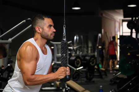 Strong Hispanic man doing cable rope pullovers at a gym.の写真素材