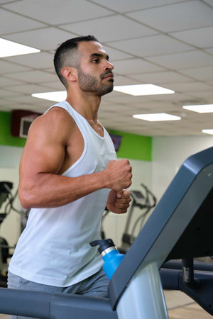Strong Hispanic man running on treadmill at a gym.の写真素材