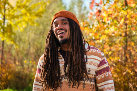 African American young man with dreadlocks laughing and looking at camera in a sunny day of autumn.の写真素材
