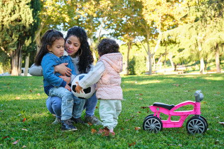 Dominican mother teaching her kids to share the soccer ball. Easing sibling rivalry.の写真素材