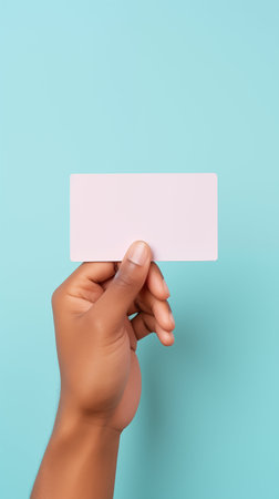 Hand holding a blank card over pastel blue background. Generative AI.の素材