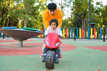 Ecuadorian father playing with his one year old daughter on a balance bike in a park.の写真素材