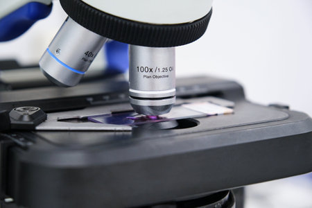 Close up of microscope slide in a microscope lens. Scientific research concept.