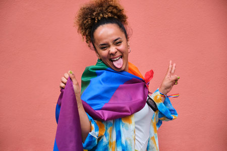 Lesbian woman is posing with a rainbow flag celebrating Pride Month.