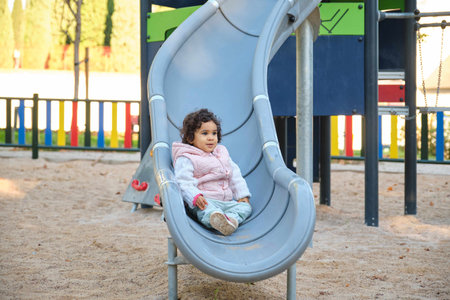 One year old Latin girl playing at a slide at a park.の写真素材