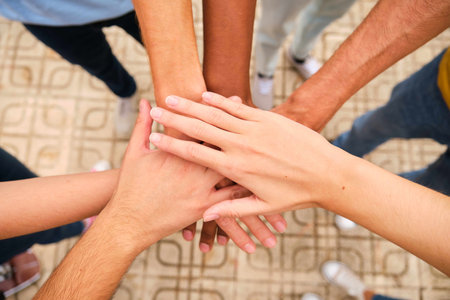 High angle view of multiracial friends stacking hand together at street.