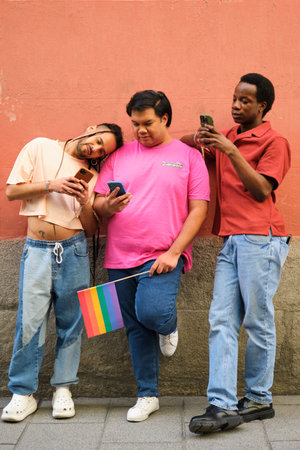 Three gay men are standing next to each other, all looking at their cell phones at street.