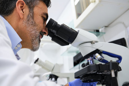 Middle aged scientist looking through microscope, working in a biochemical laboratory. Science research.の写真素材