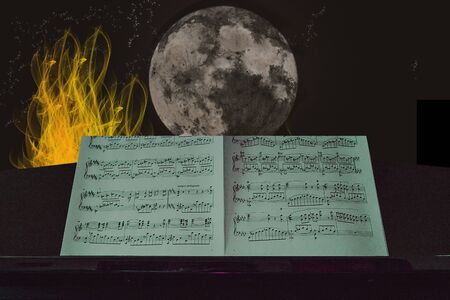 Grand piano on an evening with a full moon with fire on the leftの写真素材