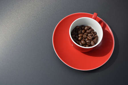 Coffee beans in a red espresso cup seen from above on a shiny gray backgroundの写真素材