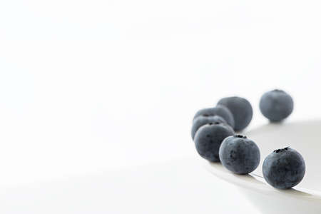 Blue berries on a white plate and white backgroundの写真素材
