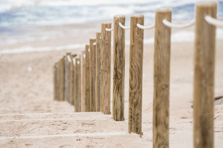 Wooden fence on stairs on the beach leading to the seaの写真素材