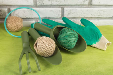 Garden tools, working gloves and balls of twine on a green background