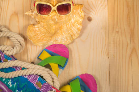 beach bag, flip flops, sunglasses, shell on wooden background. Top viewの写真素材