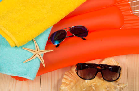 Summer beach accessories on swimming mattress. Sunglasses, towel seashells.の写真素材