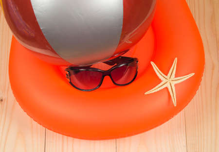 swimming ring, ball, sunglasses and starfish on wooden background. Top viewの写真素材