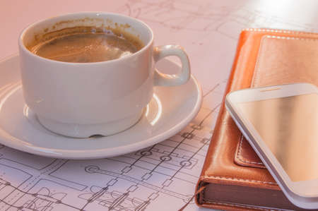Cup of coffee, cellphone, diagram, drawing, glasses on table top viewの写真素材