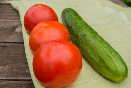 The concept of healthy eating with organic cucumber and cherry tomatoes on wooden tableの写真素材