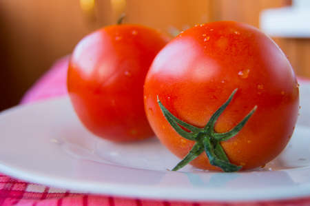 Closeup of fresh ripe tomatoes on a white plate, selective focus
