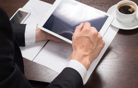 Businessman at his workplace with a Cup of coffee and a tablet computer. Close-upの写真素材