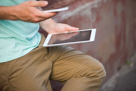 Close up of a man using mobile smart phone and tablet, selective focus, copy space.