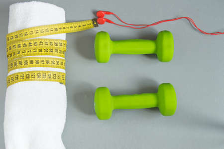 Dumbbells green, red headphones white towel, and measuring tape. Top view, Fitness and diet concept backgroundの写真素材